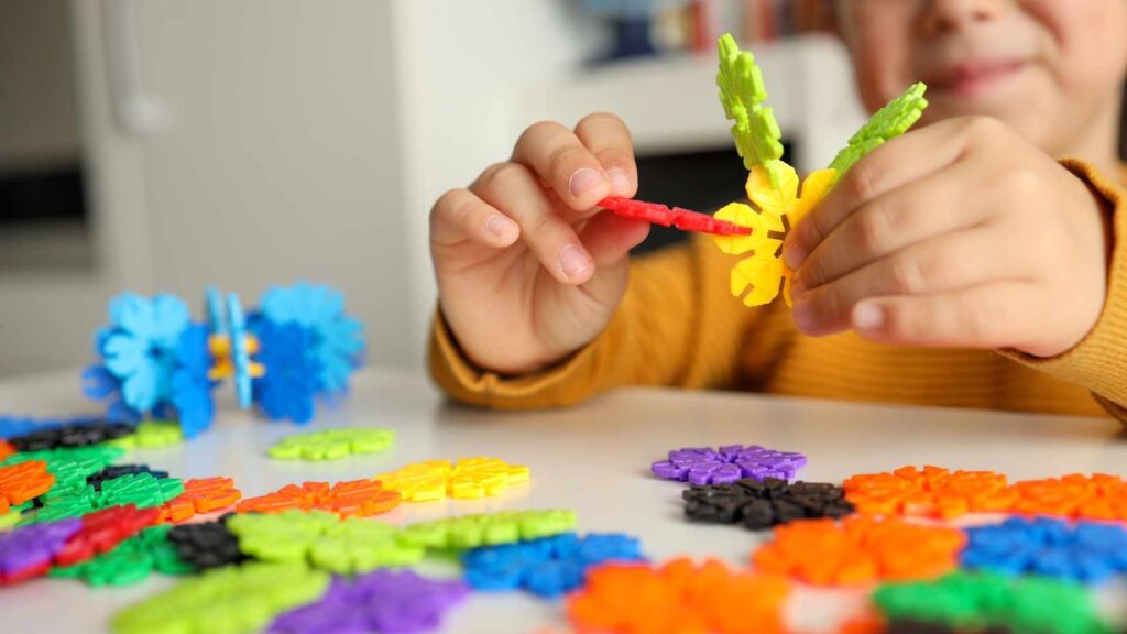Child connecting colorful building pieces during a fine motor skills activity.