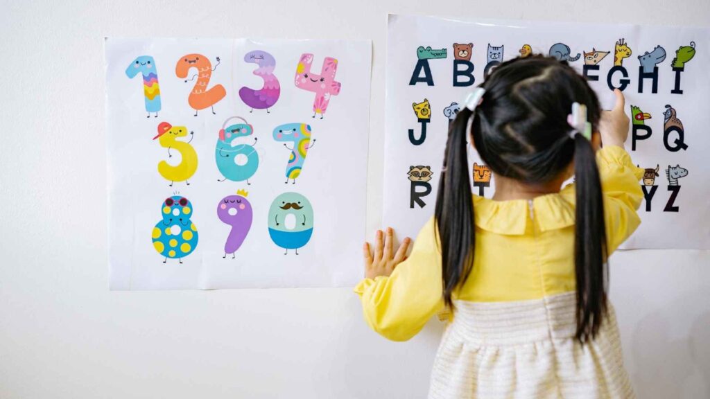 Young child pointing to letters on a classroom alphabet poster.